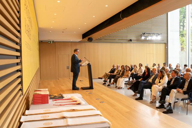 Un ponente habla frente a una audiencia en un evento formal.