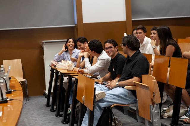 Un grupo de jóvenes se ríen y conversan en un aula.