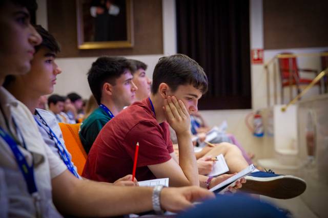 Un grupo de jóvenes observa atentamente en un evento educativo.