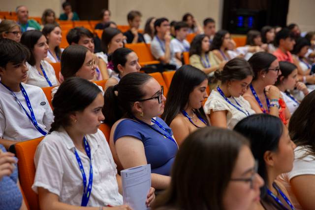 Un grupo de jóvenes presta atención durante una conferencia en un auditorio.