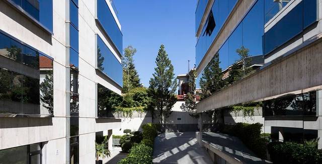 Un complejo arquitectónico moderno con fachadas de vidrio y vegetación en el interior.