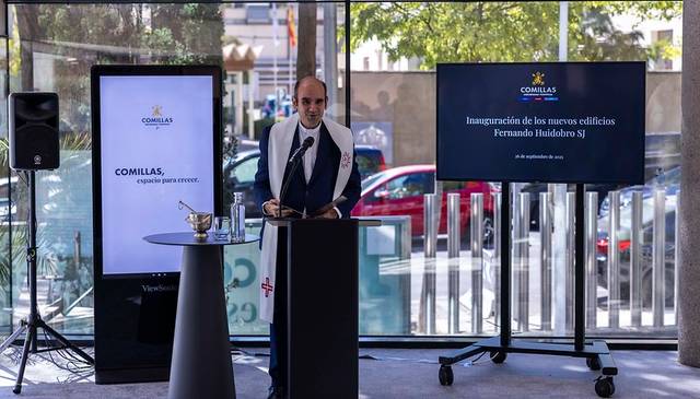 El evento de inauguración de los nuevos edificios en Comillas se celebra con un discurso frente a una pantalla grande.