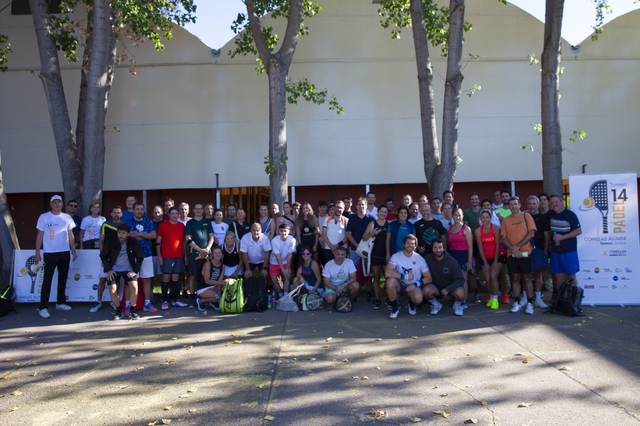 Un grupo de personas posando junto a un cartel en un evento deportivo.