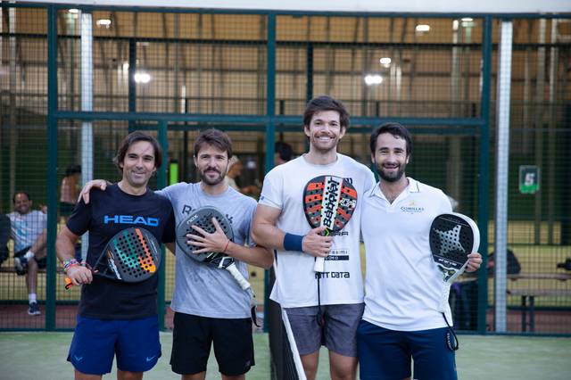 Cuatro jugadores de pádel posan juntos en una pista.