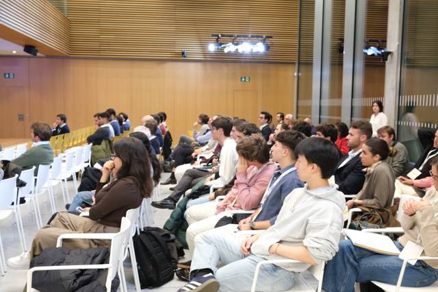Un grupo de personas sentadas en un auditorio durante una presentación.