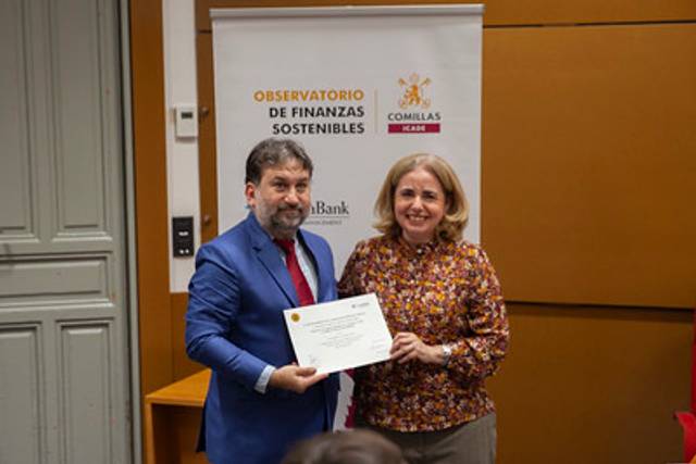 Dos personas posan juntas en un evento, sosteniendo un certificado frente a un fondo con el logotipo de un observatorio de finanzas sostenibles.