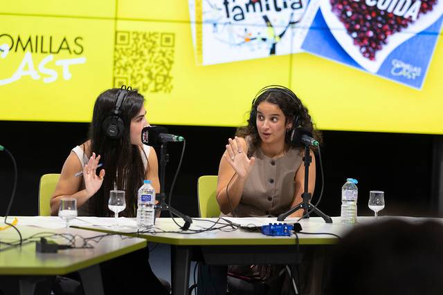 Dos mujeres están participando en un programa de radio, conversando animadamente mientras usan auriculares.