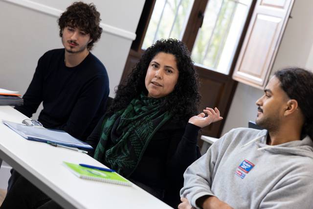 Un grupo de tres personas sentadas en una mesa durante una conversación.
