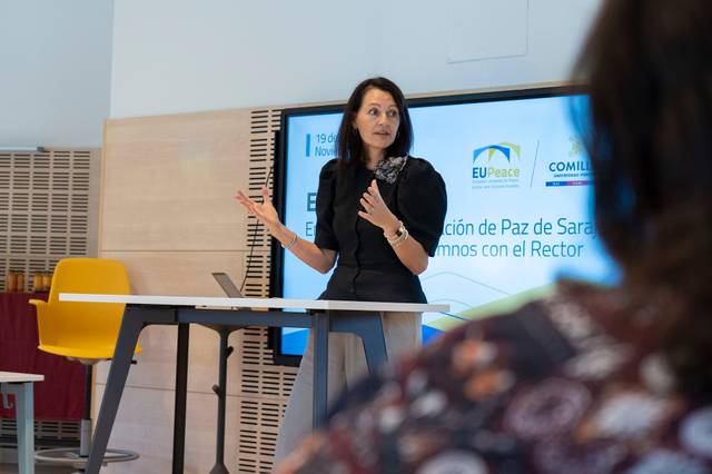 Una mujer habla en una conferencia sobre la paz mientras una audiencia escucha.