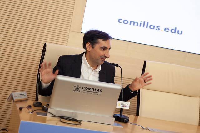 Un hombre habla animadamente en una conferencia con un ordenador portátil frente a él.