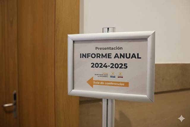 Un cartel que anuncia la presentación del informe anual 2024-2025 en una sala de conferencias.