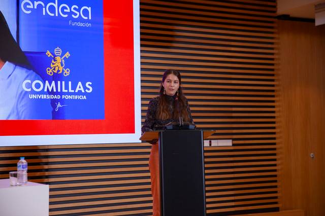 Una mujer habla en un podio durante un evento en la Universidad Pontificia Comillas.