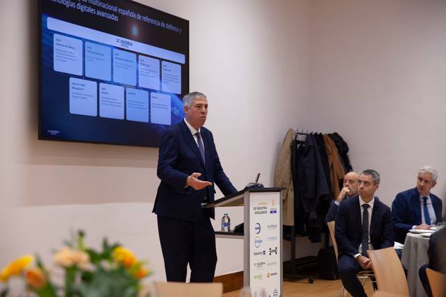 Un hombre da una presentación en una reunión mientras otros asistentes lo observan atentamente.