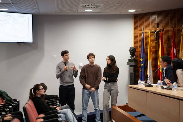 Un grupo de estudiantes presenta un proyecto ante un público en una sala de conferencias.