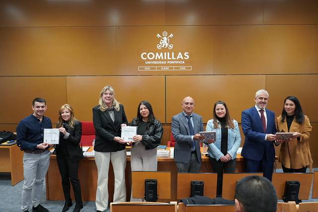 Un grupo de personas sosteniendo certificados en un evento en la Universidad Pontificia Comillas.