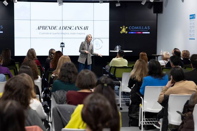 Una conferencista presenta el tema 'Aprende a descansar' a un grupo de personas en un evento en Comillas.