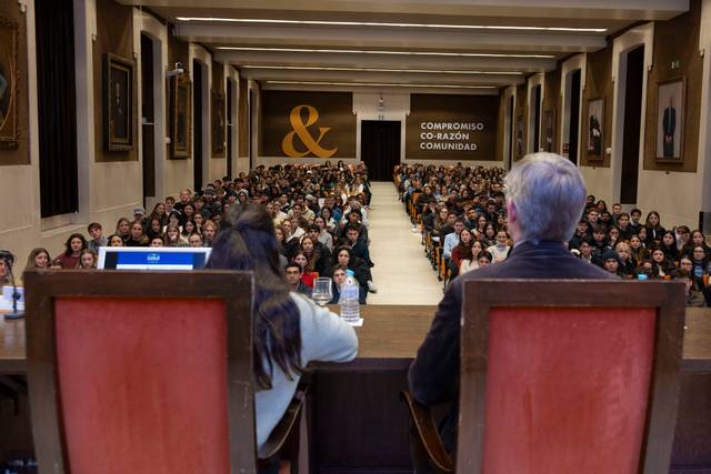 Una conferencia en un auditorio con un gran número de estudiantes presentes.