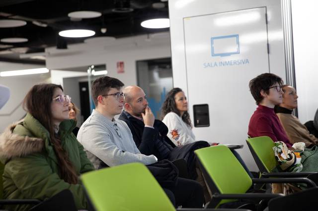 Un grupo de personas asiste a una presentación en una sala moderna.