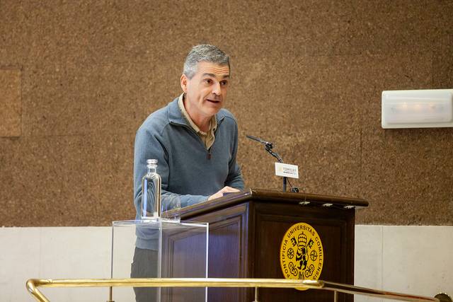 Un hombre habla en un podio en un evento académico.