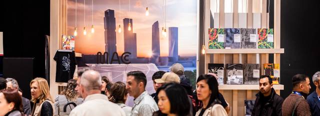 Una multitud de personas en un evento social con un fondo de edificios y luces colgantes.