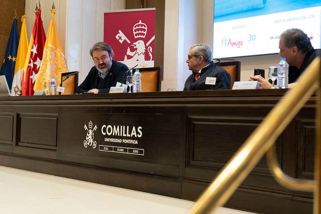 Una reunión en la Universidad Pontificia Comillas con varias personas sentadas en una mesa frente a un público.