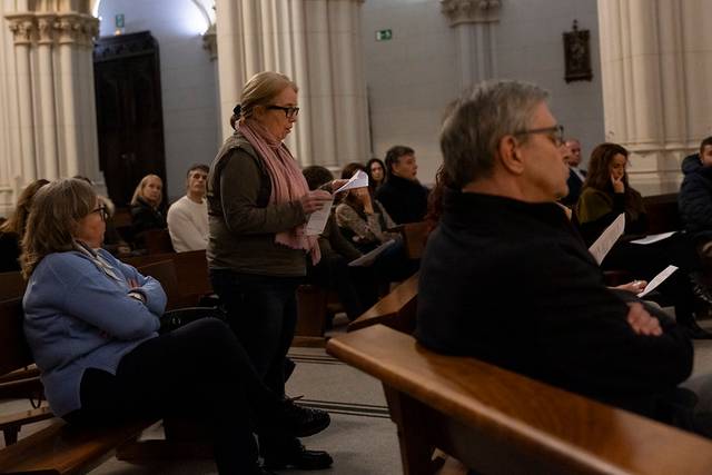 Un grupo de personas en un interior, algunas sentadas y otras de pie, parecen estar en un momento de reflexión o ceremonia.