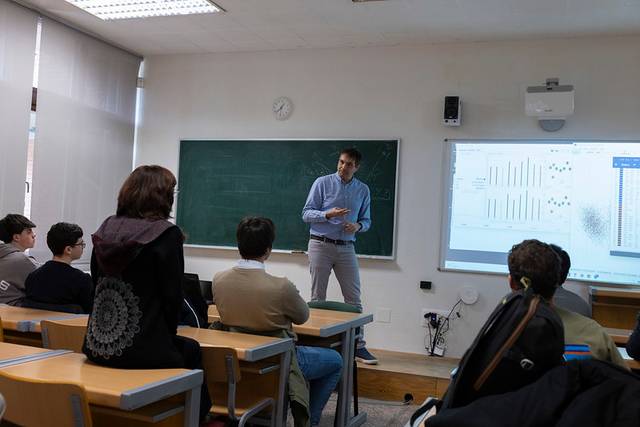 Un profesor está dando una clase frente a un grupo de estudiantes en un aula.