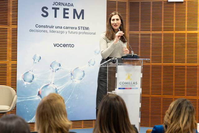 Una mujer habla en un evento sobre carreras STEM mientras un auditorio escucha atentamente.