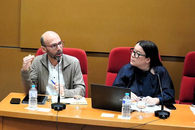 Dos personas conversando en una mesa durante un evento o reunión.