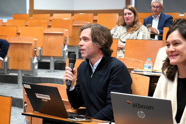 Un hombre habla en un salón de conferencias mientras un grupo de personas lo escucha.