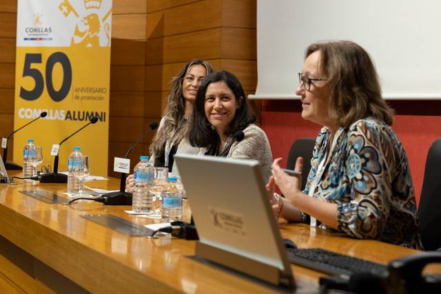 Un grupo de mujeres discutiendo en una mesa durante un evento en la universidad.