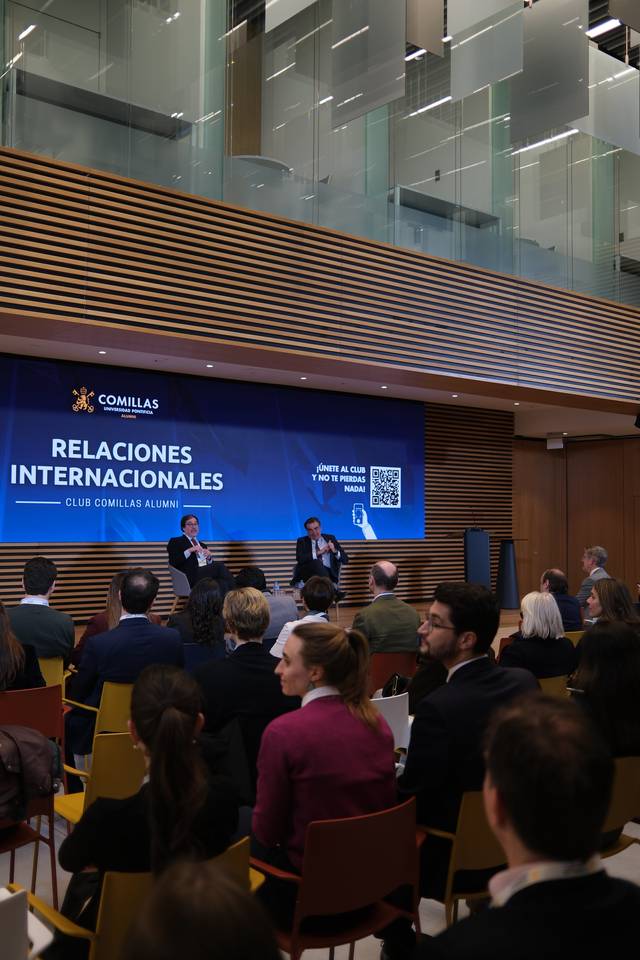 Un evento del Club Comillas Alumni sobre relaciones internacionales con un público atento en un ambiente moderno.