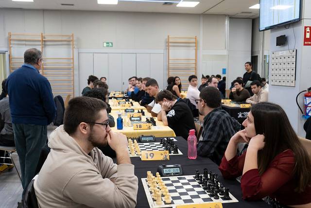 Un torneo de ajedrez en un salón donde varios jugadores compiten en mesas organizadas.