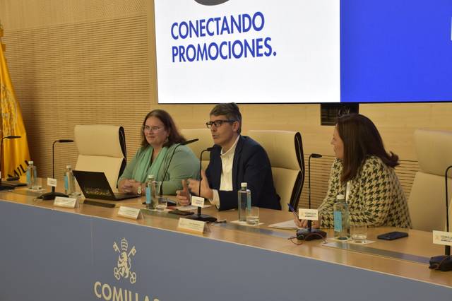 Una mesa de conferencias donde tres personas participan en una charla sobre promociones.