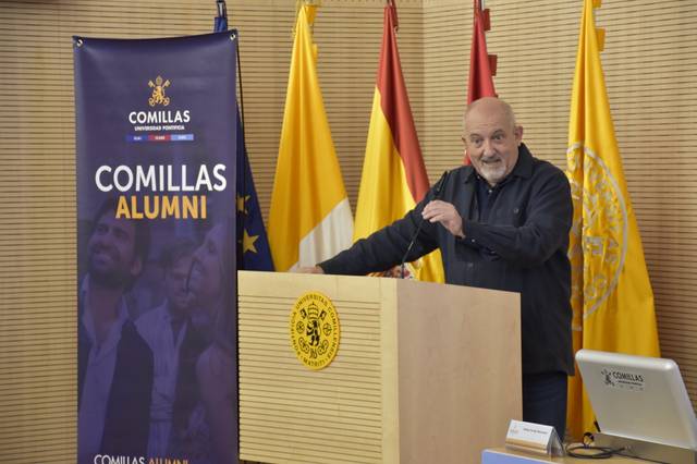 Un hombre habla en un evento frente a un podio con un banner de Comillas Alumni.