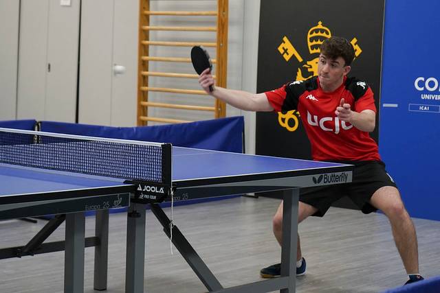 Un joven está jugando al tenis de mesa en una sala deportiva.