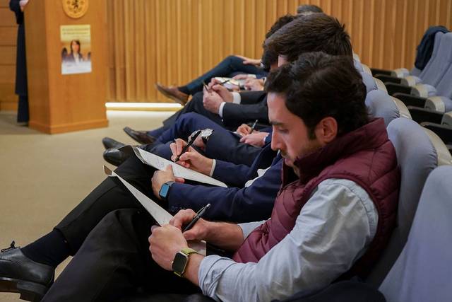 Un grupo de personas sentadas en un auditorio tomando notas durante una presentación.