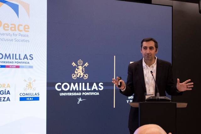 Un presentador habla en un evento relacionado con la Universidad Pontificia Comillas.