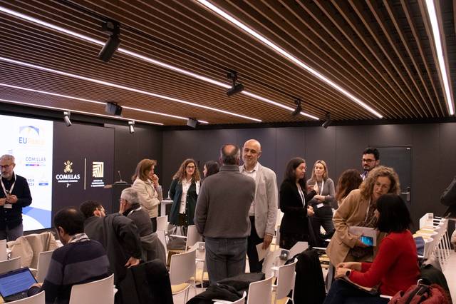 Un grupo de personas conversando en un salón de conferencias moderno.