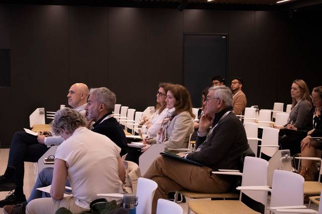 Un grupo de personas sentadas en un auditorio escuchando atentamente.
