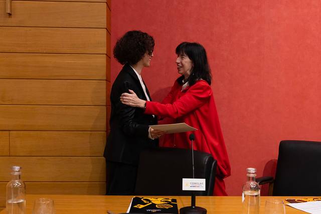 Dos mujeres se están abrazando en un contexto formal.
