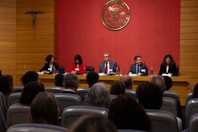 Un panel de discusión con varios ponentes en una sala llena de público.