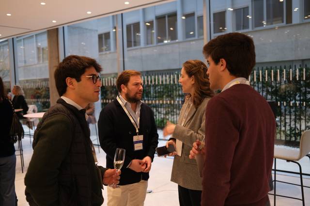 Un grupo de cuatro personas conversando en un evento social con copas en la mano.