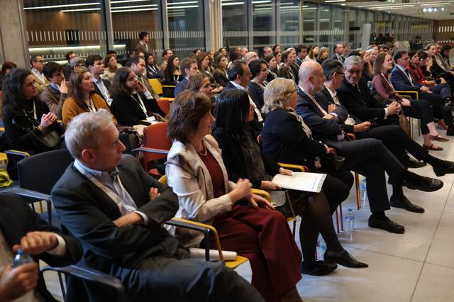 Una multitud de personas sentadas en un evento o conferencia, prestando atención al orador.