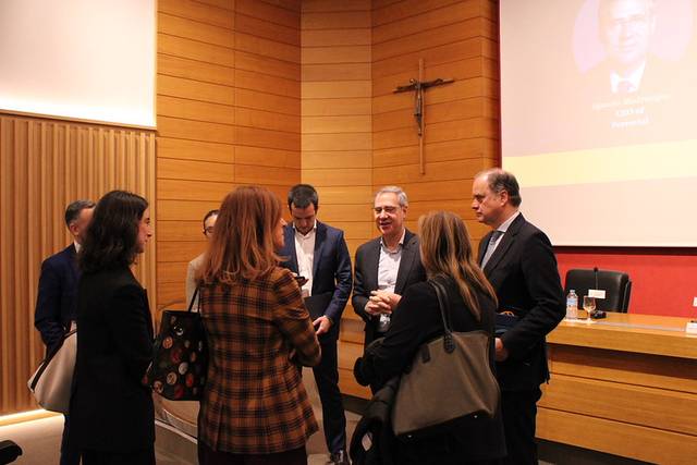 Un grupo de personas conversando en un evento en un auditorio.