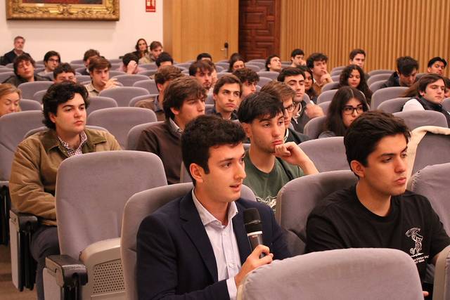 Un grupo de estudiantes escucha atentamente a un orador en un auditorio.