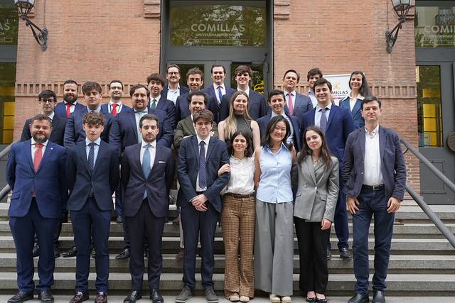 Grupo de personas posando en la entrada de un edificio con el nombre Comillas.