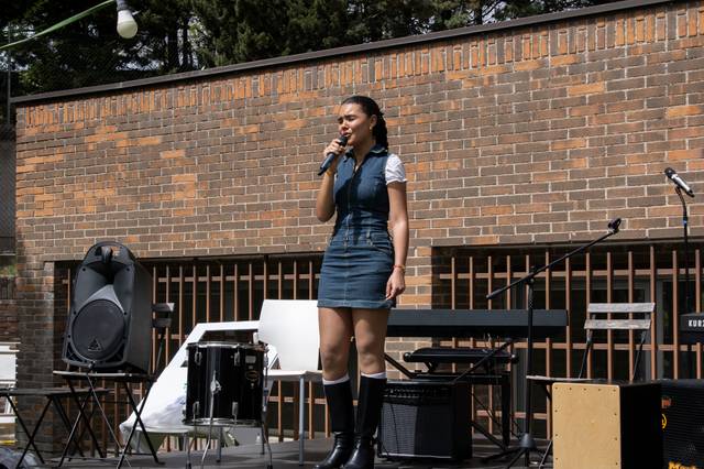 Una mujer canta con un micrófono sobre un escenario al aire libre.