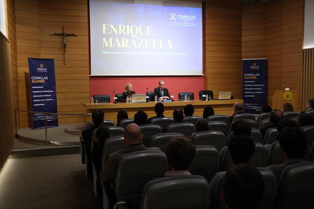 Una conferencia en un auditorio con un público sentado y dos ponentes en el estrado.