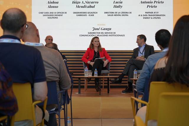 Un panel de discusión con cuatro oradores en un evento corporativo.